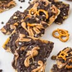 Pretzel bark on a white background with chocolate and pretzels scattered around it.