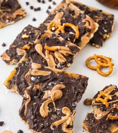 Pretzel bark on a white background with chocolate and pretzels scattered around it.