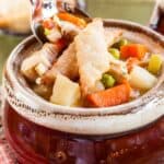 Soup topped with pie crust crackers in a crock with text overlay that says "Leftover Turkey Pot Pie Soup".