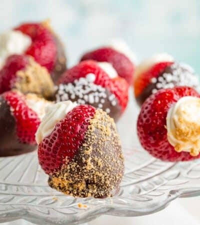 A glass cake plate with deviled strawberries dipped in chocolate.