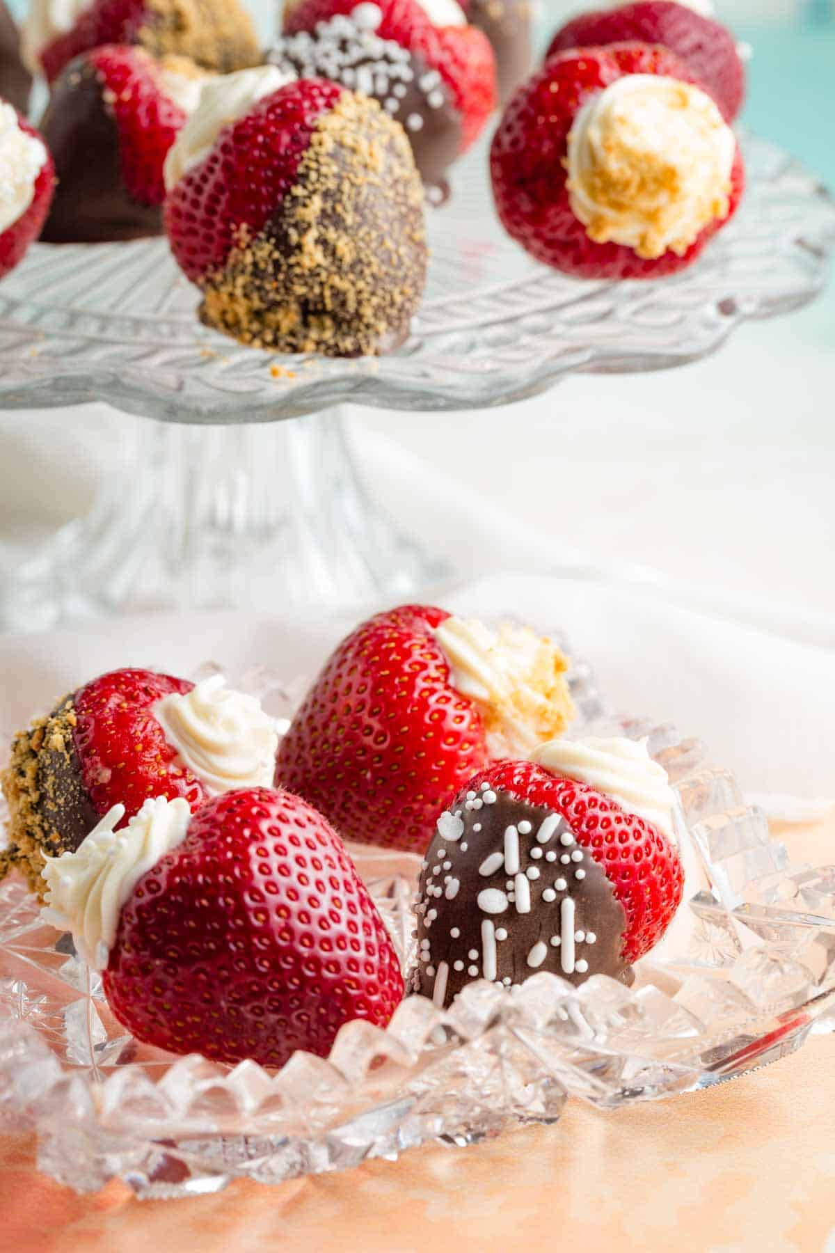 Decorative plates hold chocolate dipped cheesecake stuffed strawberries.