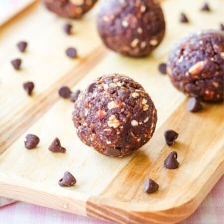 Chocolate chip cherry energy balls on a wooden board.