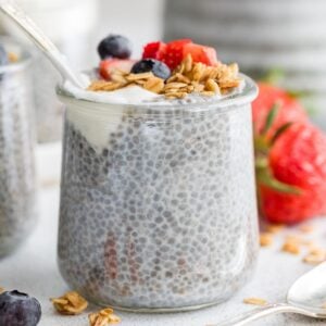 A glass jar of chia seed pudding topped with granola and berries.