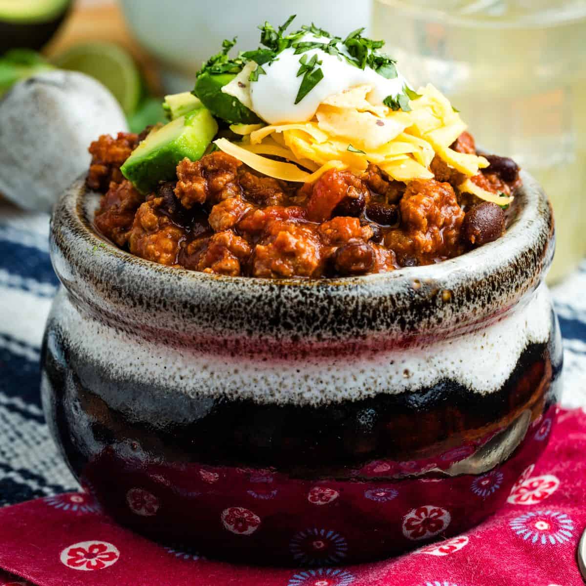 A bowl of ground turkey chili with toppings.