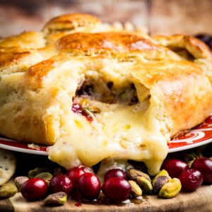 A serving platter holds a baked brie in crescent dough.