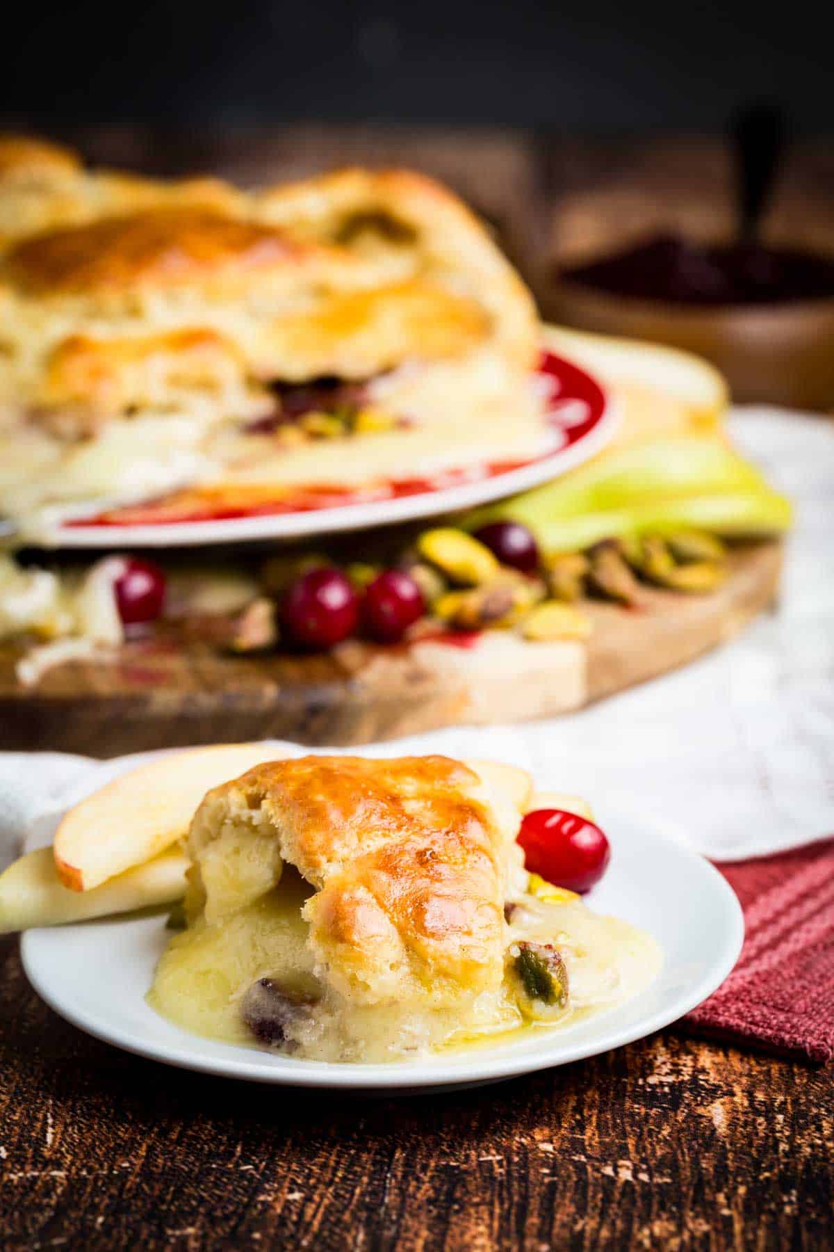 A plate of baked brie in crescent dough with a slice on a plate.