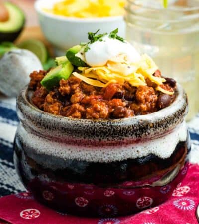 A bowl of ground turkey chili with toppings.