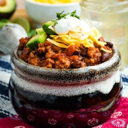 A bowl of ground turkey chili with toppings.