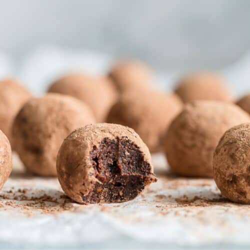 Six homemade energy balls with a bite taken of one.