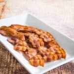 A plate of cooked bacon slices.