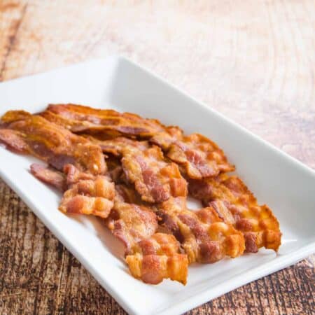 A plate of cooked bacon slices.