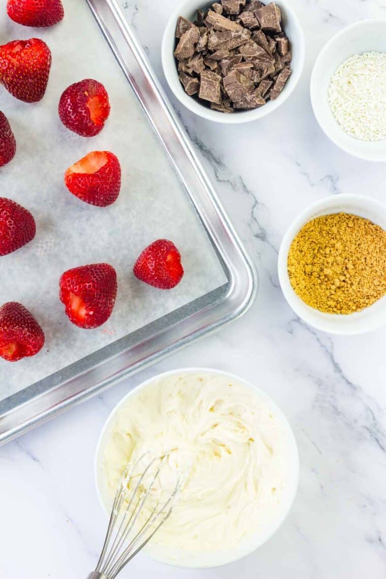 Hulled strawberries surrounded by toppings and cream cheese filling.