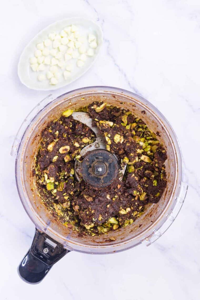 Pistachios added to a food processor of cherry energy bars dough.