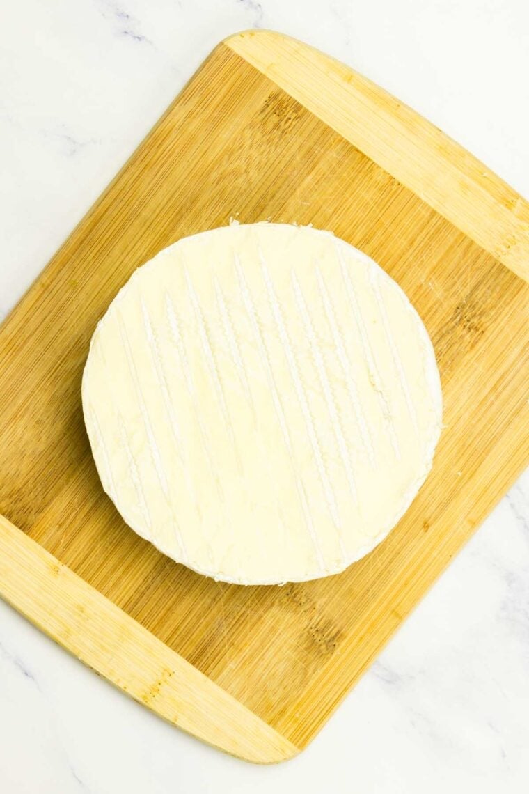 A round of brie on a cutting board.