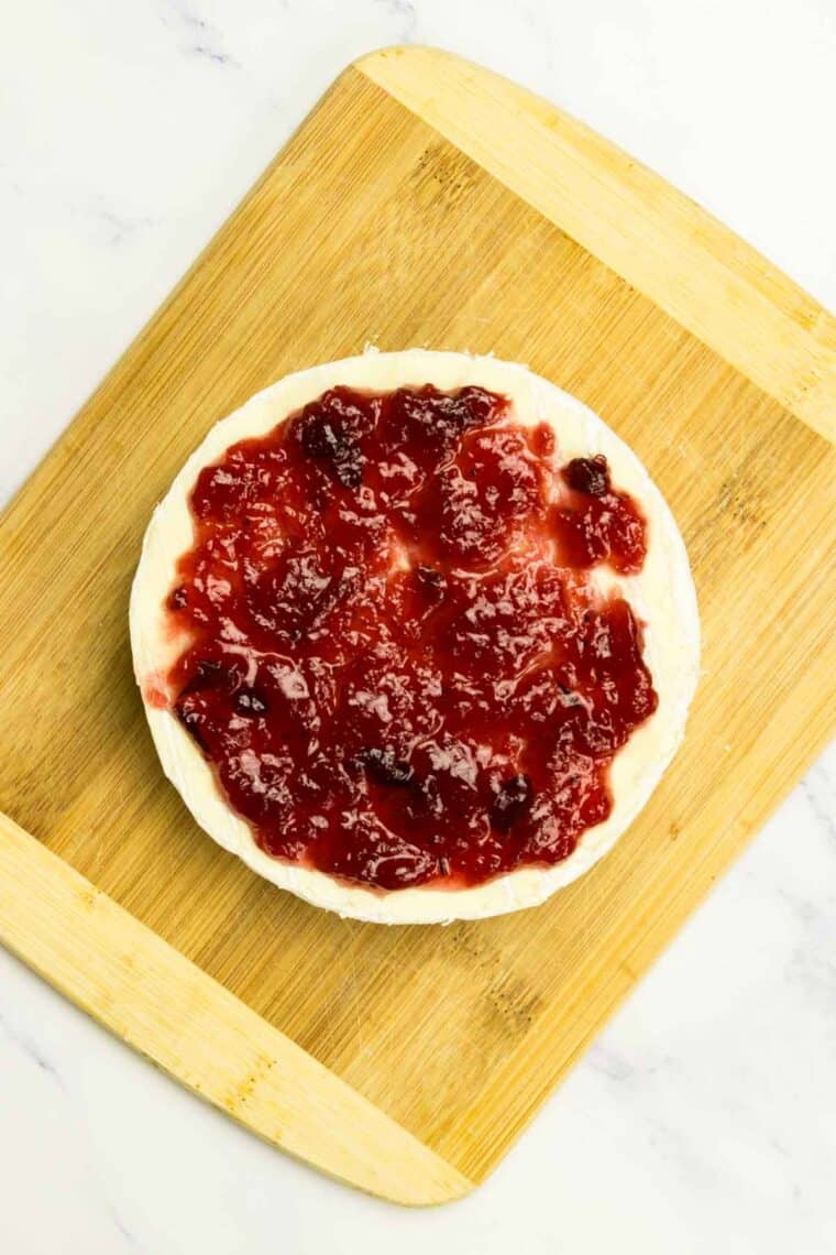 Cranberry sauce is added to the top of brie.