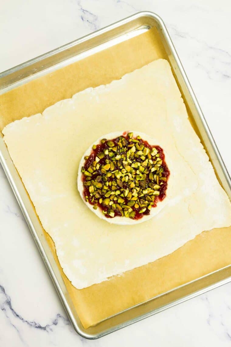 Cranberry sauce and pistachios added to a round of brie on crescent dough.