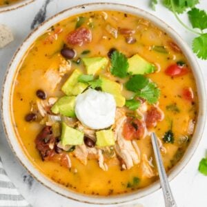 A bowl of chicken taco soup topped with avocado and sour cream.