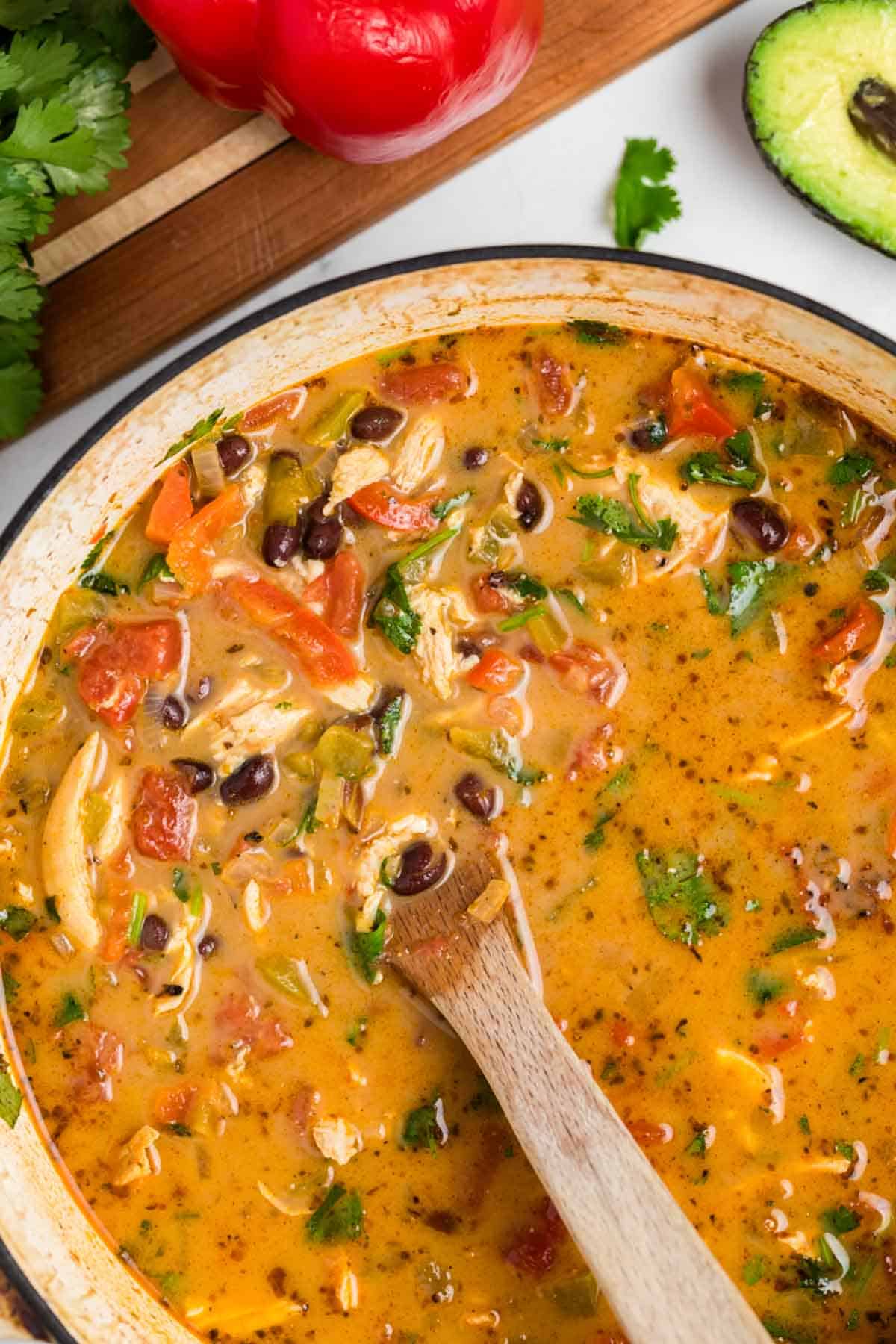 A wooden spoon stirs a pot of chicken taco soup.