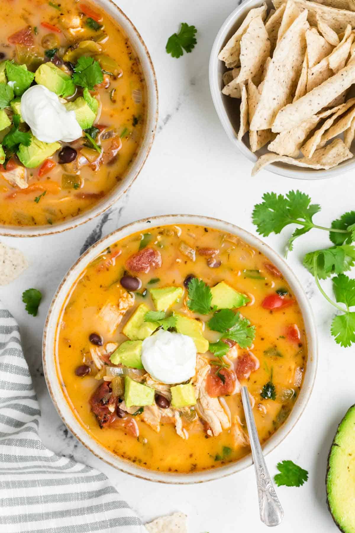 Bowls of chicken soup and a bowl of tortilla chips.