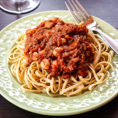 Spaghetti on a plate topped with chickpeas in tomato sauce.