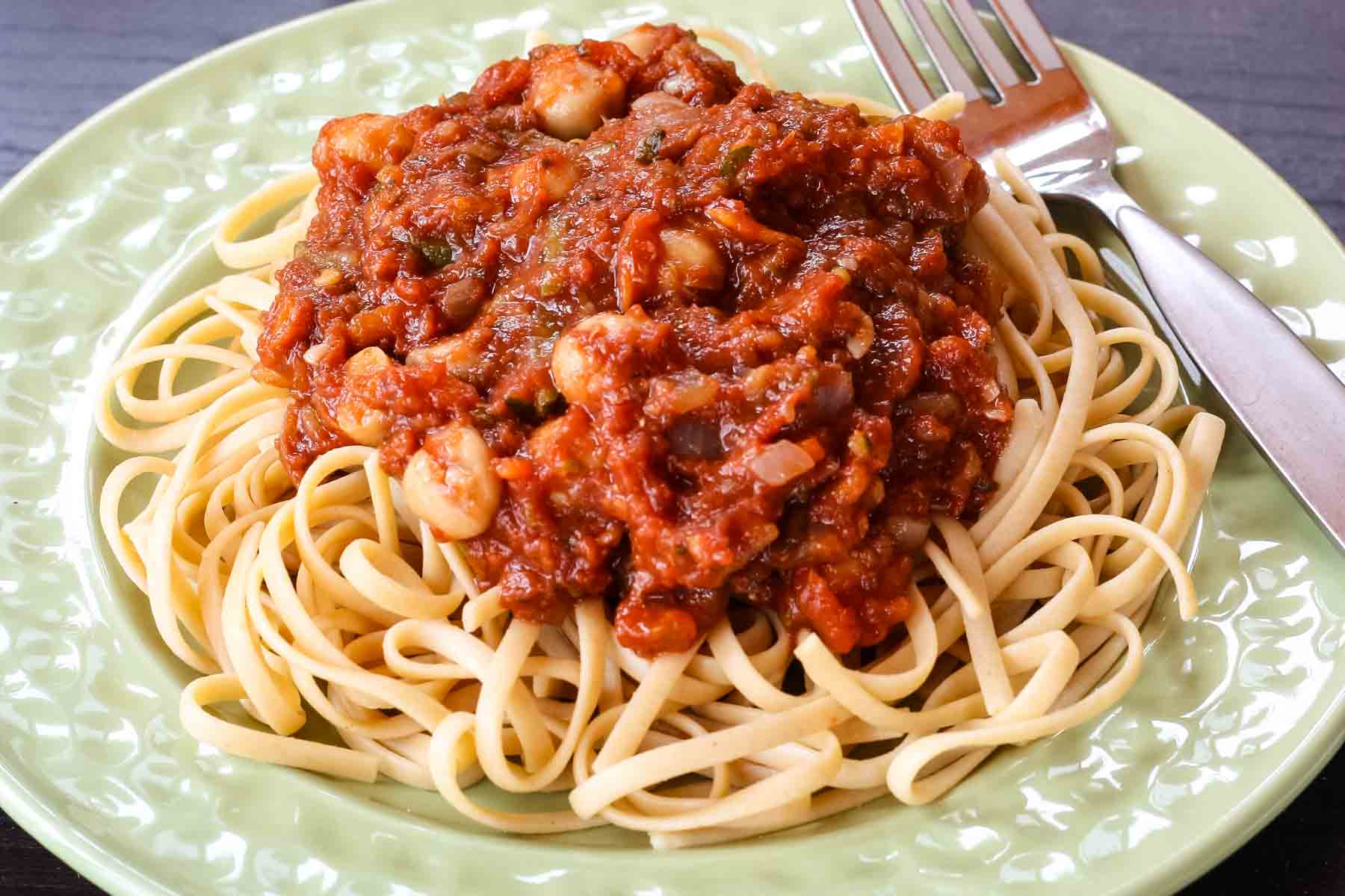 Spaghetti on a plate topped with chickpeas in tomato sauce.