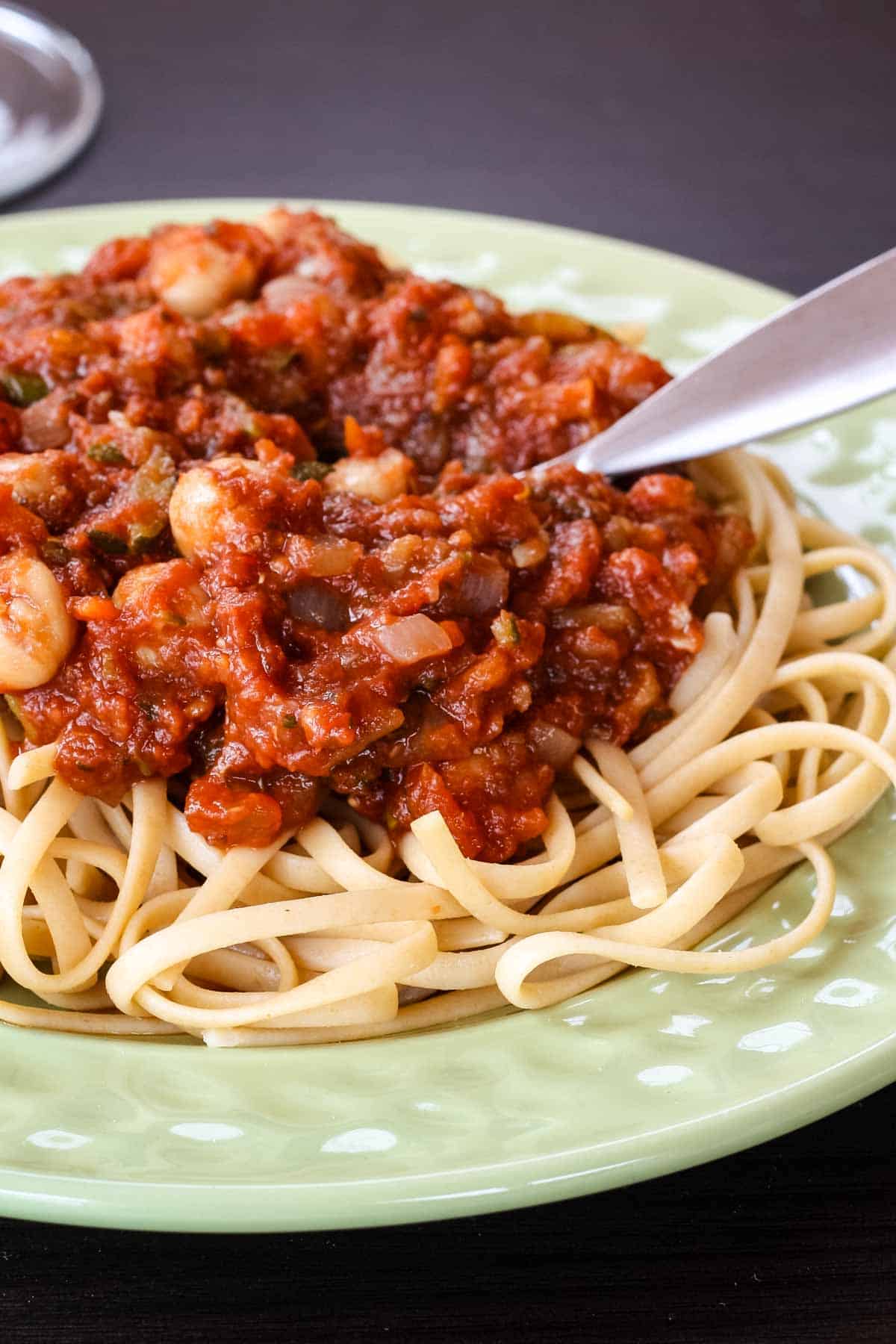 Spaghetti on a plate topped with chickpeas in tomato sauce.