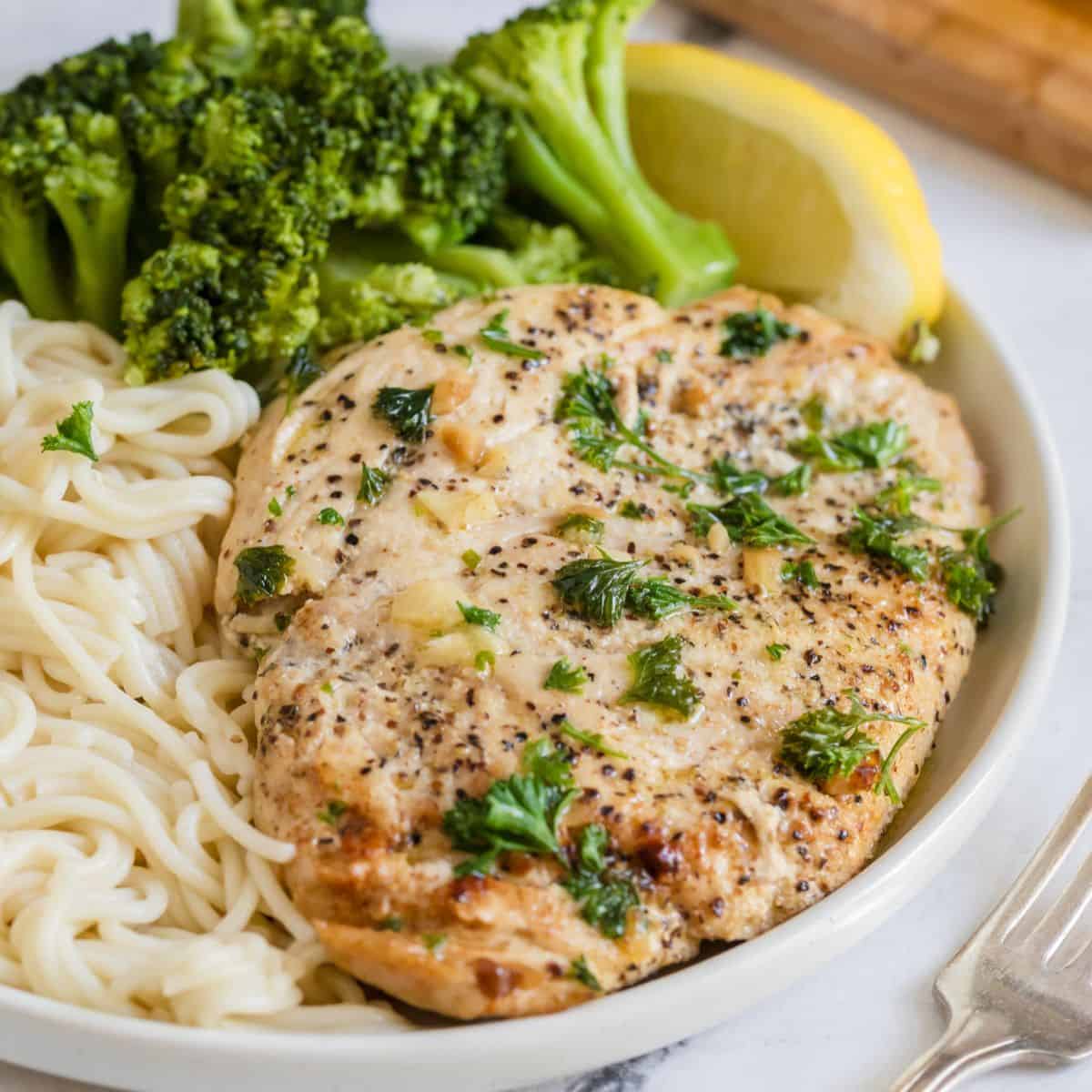 A plate with garlic butter chicken, broccoli, and noodles.