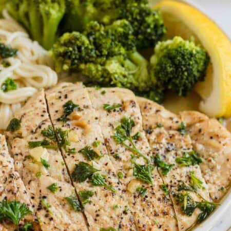 Broccoli and lemon on a plate with garlic butter chicken.