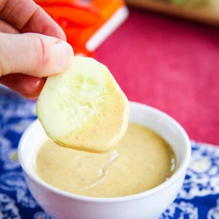 A cucumber slice after being dipped in a bowl of honey mustard dipping sauce.