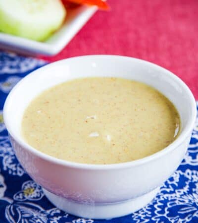 A white bowl of honey mustard dipping sauce.