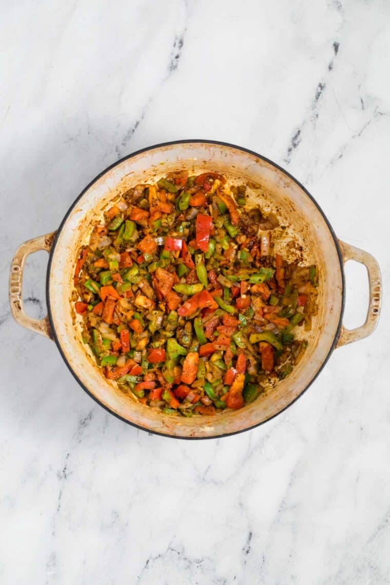 Bell peppers and onions cook in a soup pot.