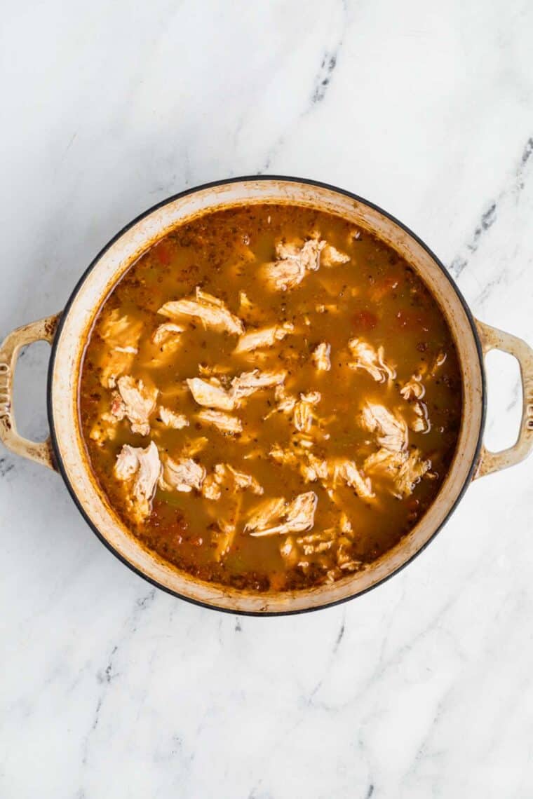 Shredded chicken is added back to a pot of soup.