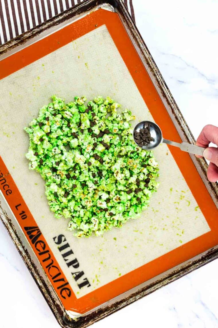 Mini chocolate chips are added to green popcorn.
