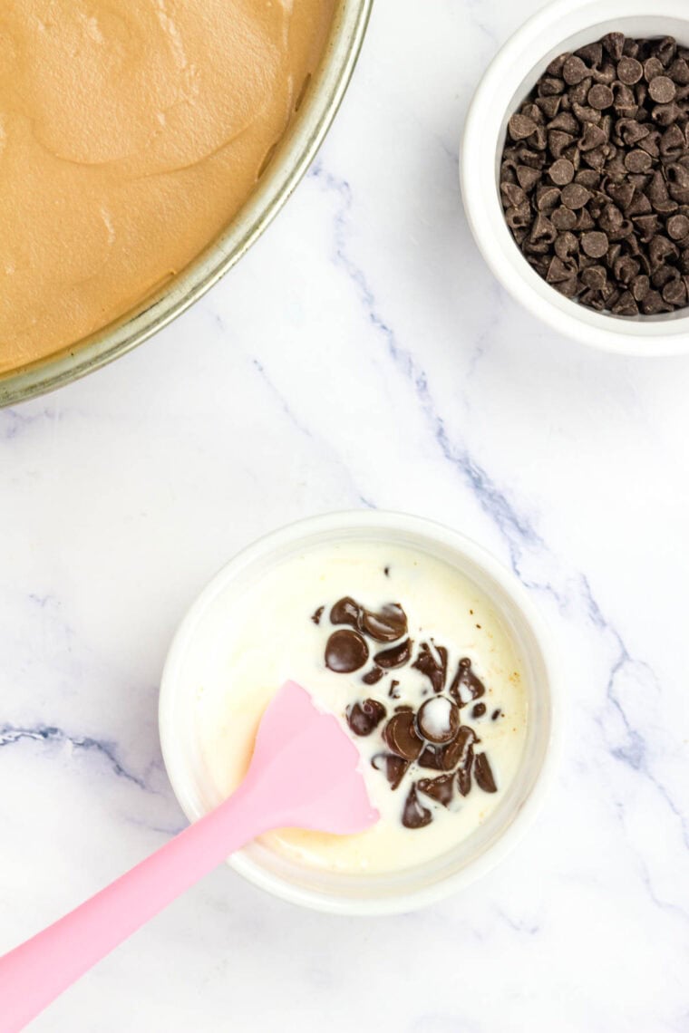 Hot cream is stirred with chocolate chips.