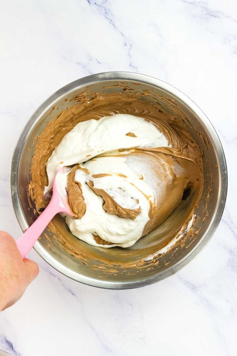 Whipped cream added to cheesecake filling in a bowl.