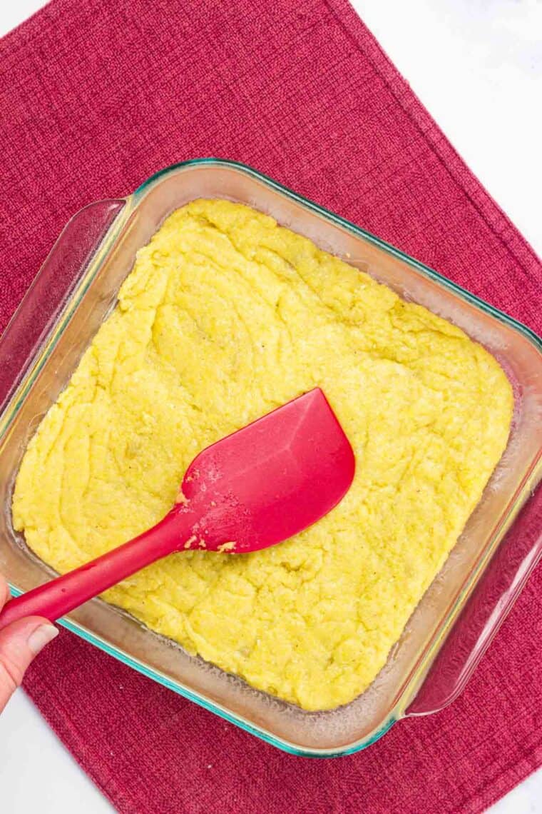 Polenta being spread in a baking dish.