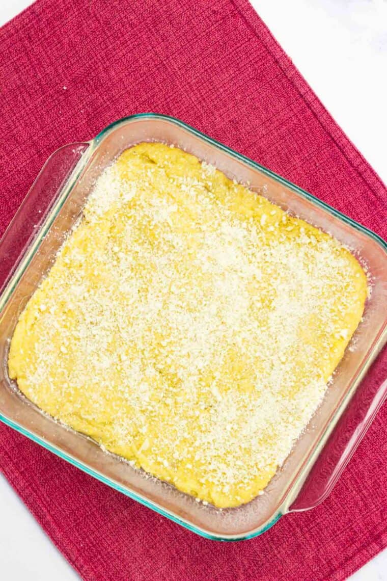 Polenta sprinkled with parmesan cheese in a baking dish.