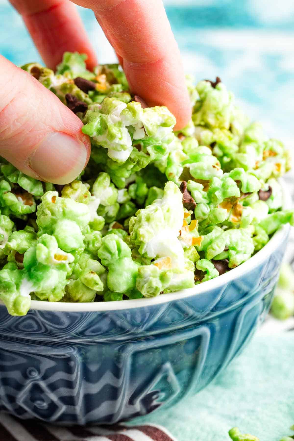 A hand picks up some mint green popcorn.