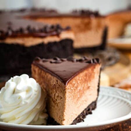 A scoop of whipped cream next to a slice of Nutella cheesecake.