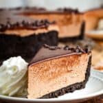 A slice of Nutella cheesecake on a plate with a swirl of whipped cream with text overlay that says "No-Bake Nutella Cheesecake".
