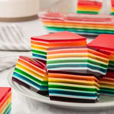 Squares of rainbow jello on a plate.