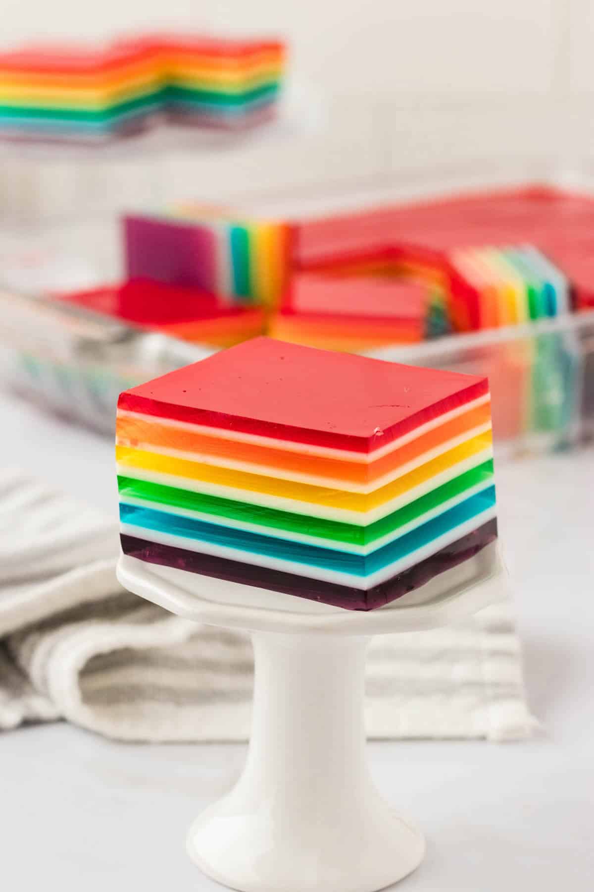 A square of rainbow jello on a small stand.