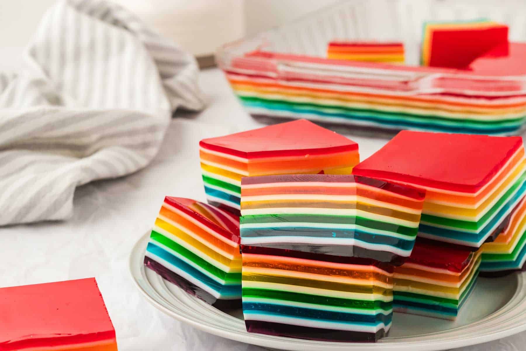A plate stacked with colorful squares of rainbow jello.