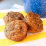 Mini carrot zucchini muffins on a striped napkin next to a blue cup.