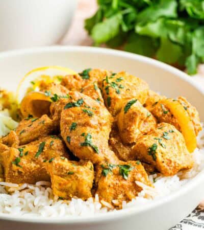 Slow cooker butter chicken on top of white rice in a bowl.