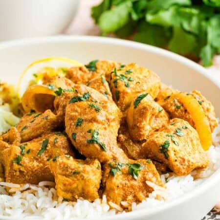 Slow cooker butter chicken on top of white rice in a bowl.