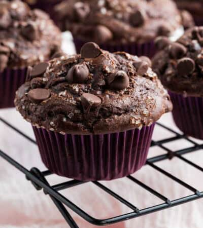Chocolate chip topped gluten free double chocolate muffins on a wire rack.