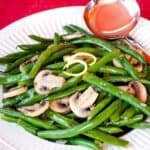 A bowl of green beans with sliced sauteed mushrooms with text overlay that says "Lemon Green Beans & Mushrooms".