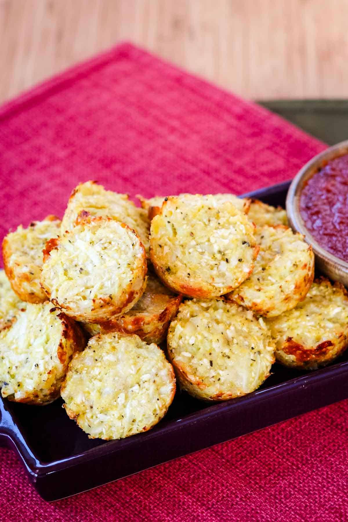 A plate of cauliflower tots on a dish on top of a red placemat.