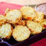Cauliflower tots piled up on a purple dish.